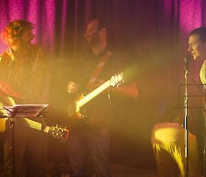 Three of the band members on guitar (acoustic, electric and bass) enjoy a laugh