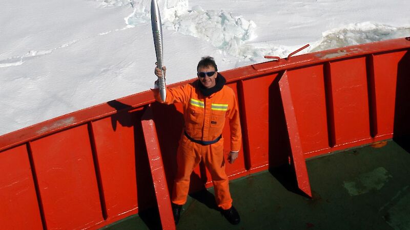 Expeditioner standing on the deck of the ship, holding the Queen’s Baton