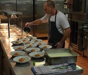 The Mawson chef, Rocket pouring a sauce into one of 15 bowls containing salmon sushi