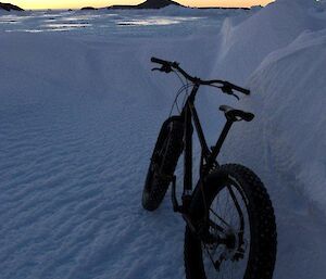Mountain bike resting against a snow drift with Welch Island in the distance