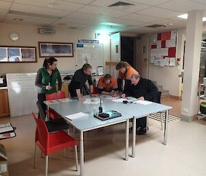 Five expeditioners participating in a briefing during a SAR exercise