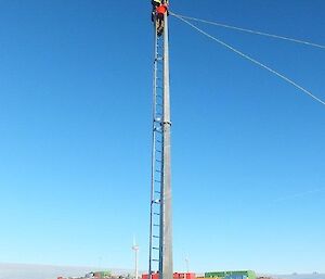 An expeditioner repairing a wind direction sensor at the top of a ten metre mast