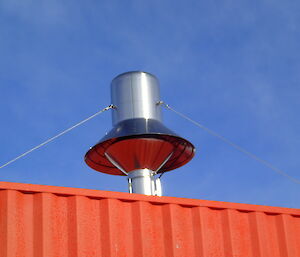 A metal pipe and hood sticking from the top of a large shipping container