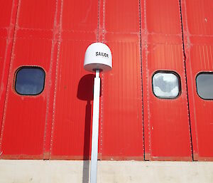 A long pole in front of a shipping container with a domed cylinder on top