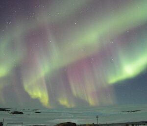 An aurora with green and pink streaks, as seen from the accommodation and living quarters