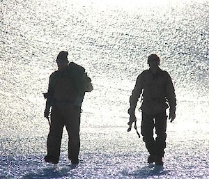 Two expeditioners walking across the ice as they make their way back to the hut