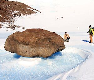 Two expeditioners stop to check out a rock caught in the frozen ice floe