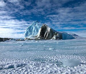 An up-turned iceberg caught in the frozen sea ice exposures the many shades of green of the algae and other organisms which usually cling to the submerged section of the iceberg. This photo was taken whilst en-route to Taylor Glacier.