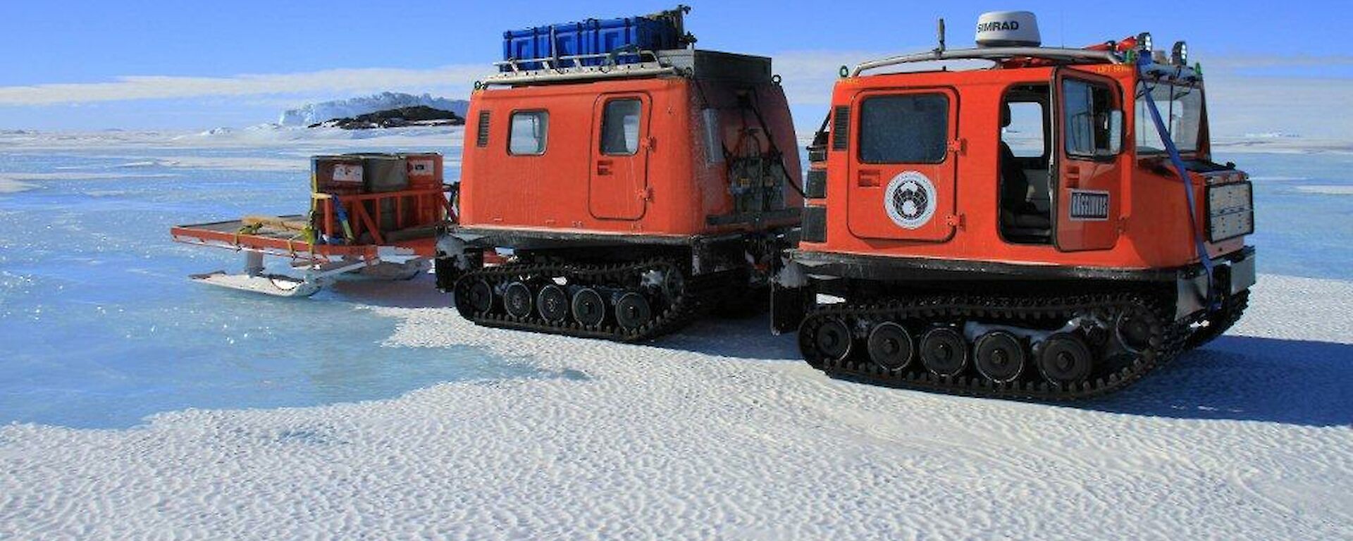 The orange Hägglunds parked on the sea ice as it makes its way to Taylor Glacier