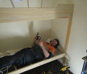 The station carpenter Chris laying on the newly constructed bed reading a book