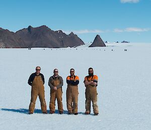 Four expeditioners stand in the middle of the icy skiway at Rumdoodle