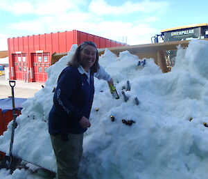 An expeditioner getting a drink out of snow in a escavator bucket