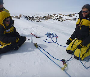 two expedtioners tying rope anchors on the snow