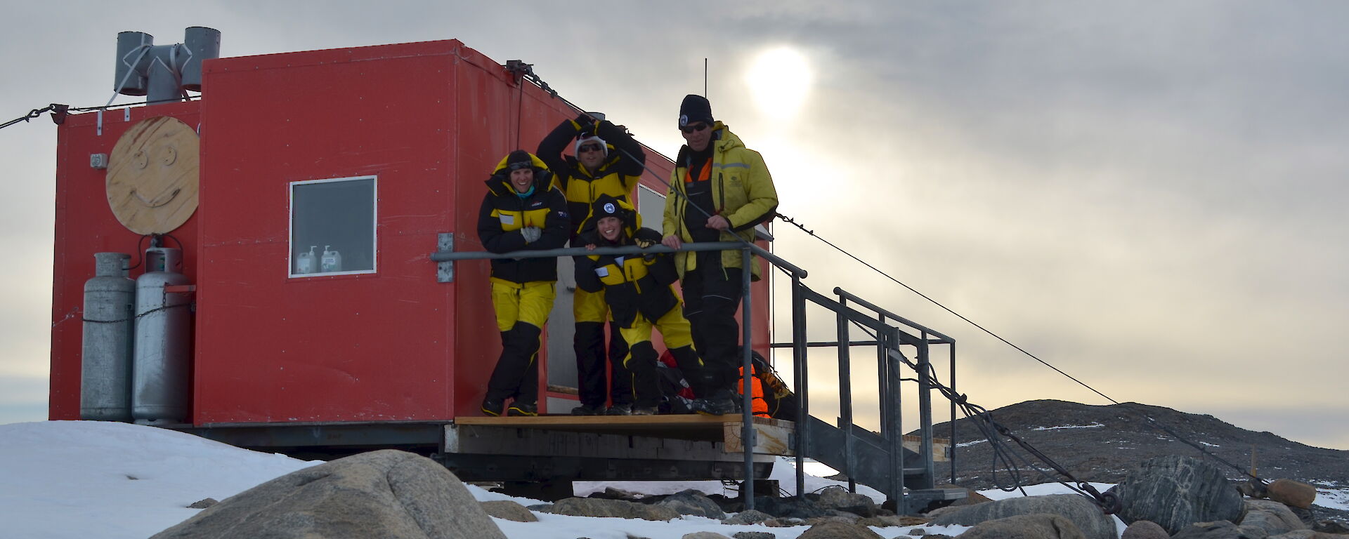 Four expeditioners satnding oustide a field hut