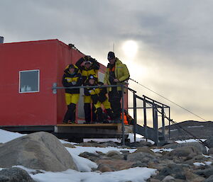 Four expeditioners satnding oustide a field hut