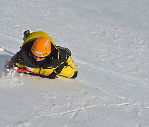 An expeditioner using an ice pick to slow his descent down a steep snow cliff