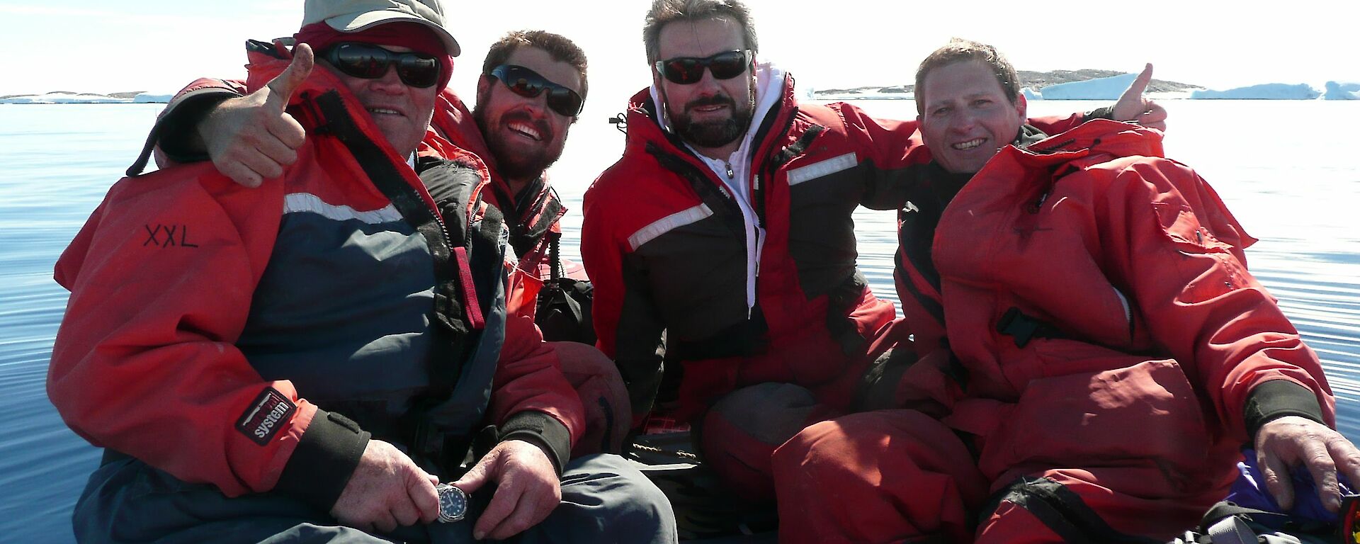 Four expeditioners posing for a photo in a inflatable rubber boat