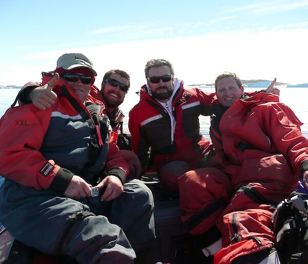 Four expeditioners posing for a photo in a inflatable rubber boat