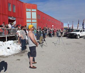 Expeditioners standing outside the red shed singing the National Anthem