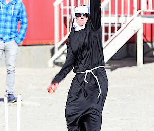 An expeditioner in a nuns outfit bowling a cricket ball