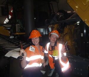 Two female expeditioners with spanners posing in front of a machine