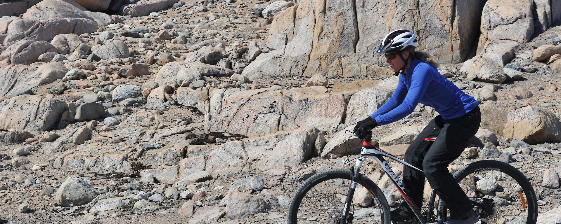 A female expeditioner riding a push bike in rocky terrain