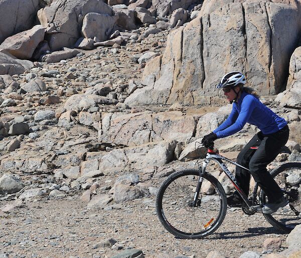 A female expeditioner riding a push bike in rocky terrain