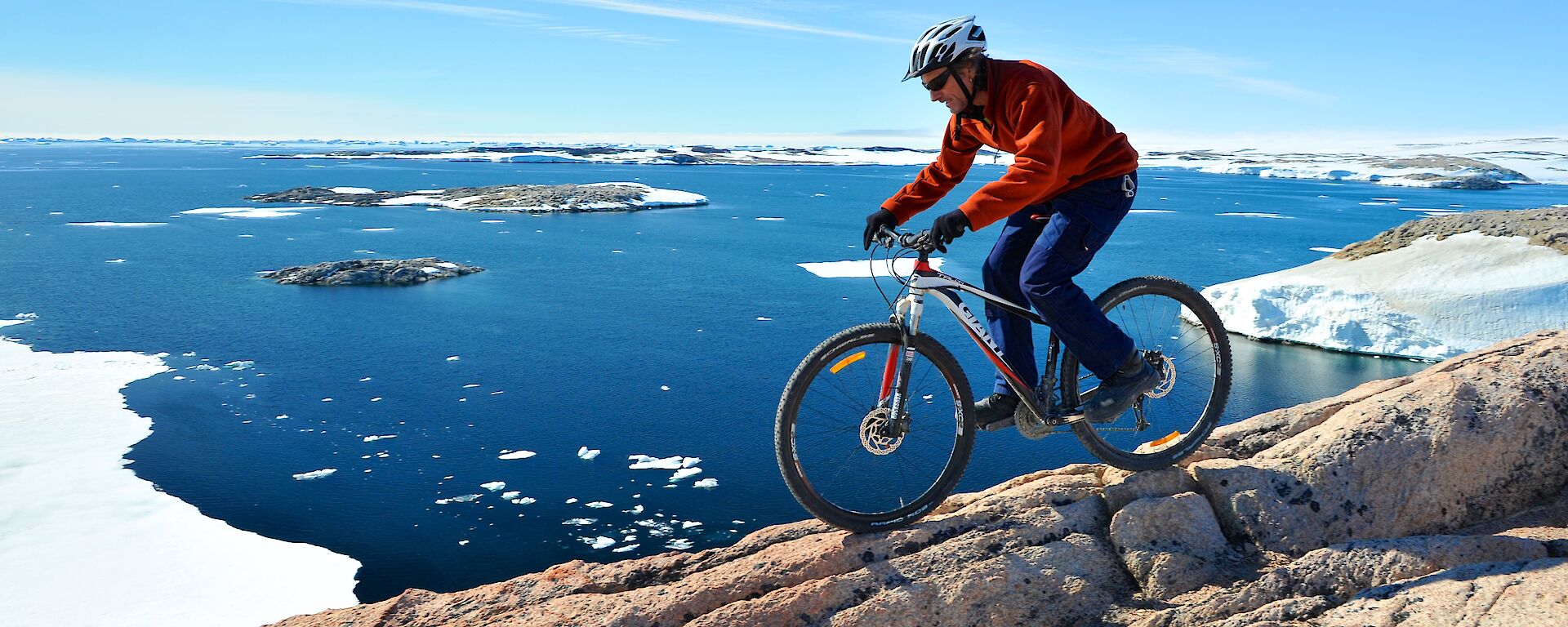 A male expeditioners riding a bike with an Antarctic backdrop