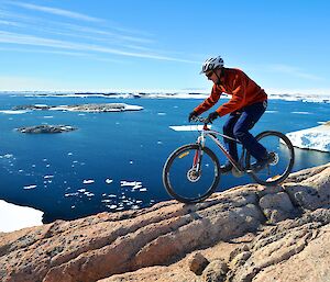 A male expeditioners riding a bike with an Antarctic backdrop