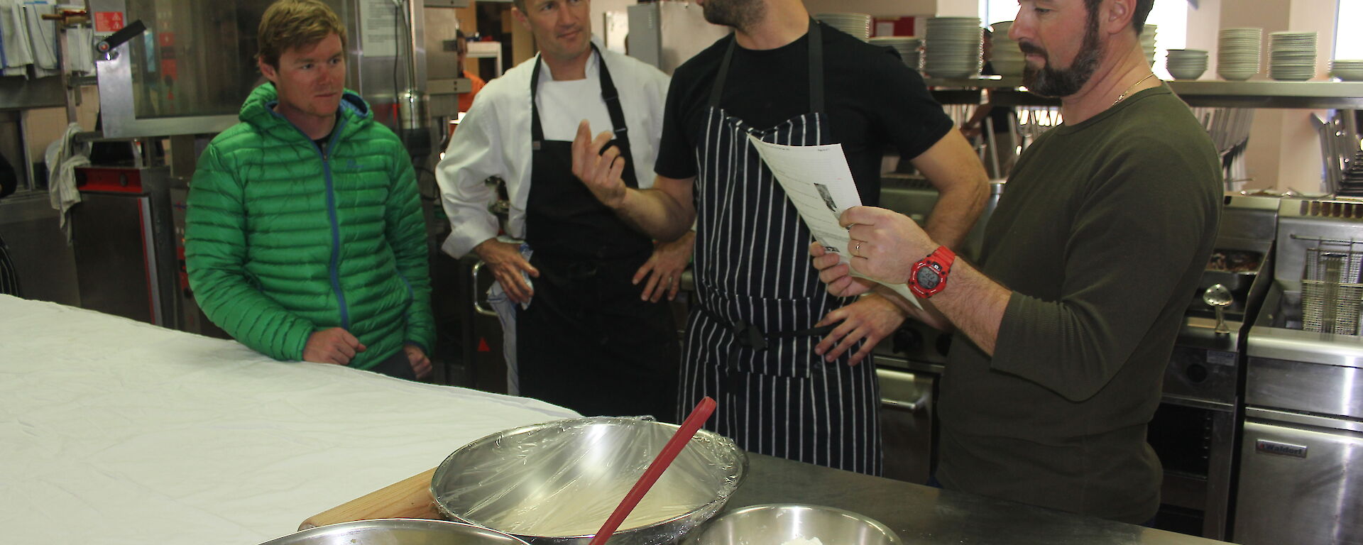 Two chefs showing a number of expeditioners how to cook