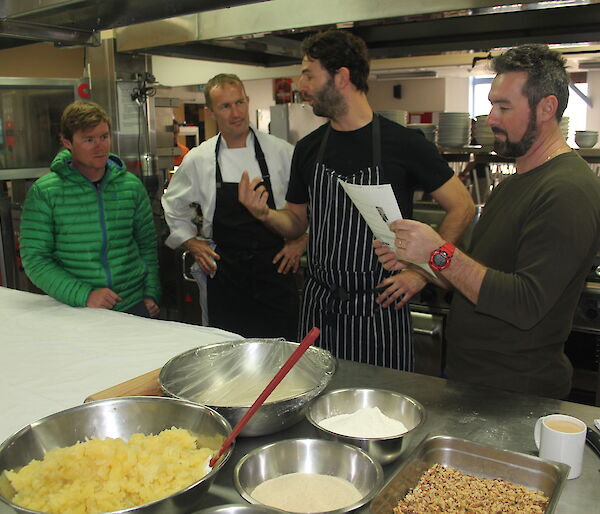 Two chefs showing a number of expeditioners how to cook