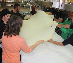 Seven expeditioners streching strudel pastry