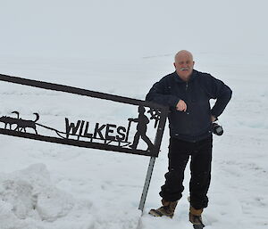 An expeditioner standing next to a Wilkes sign