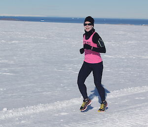 A female expeditioner jogging on the snow