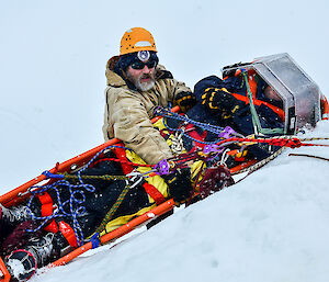 The lowering of a stretcher and patient over the cliff face