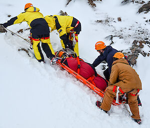 Expeditioners moving a stretcher up a snow slope