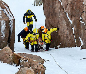 Expeditioners carrying a stretcher up a steep snow slope