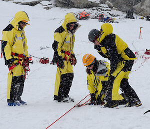 Expeditioners inserting ice anchors into the snow
