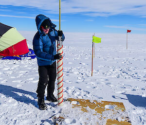 An expeditioner drilling for a snow core