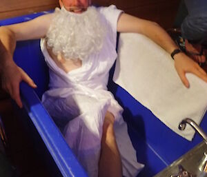 Expeditioner dressed as Archimedes lying in an empty bathtub