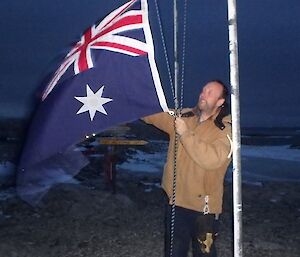 Expeditioner raises Australian flag outside in Antarctica