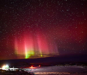 Aurora australis in the night sky just outside of Casey station — a building with light can be seen on the left side of the shot