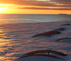 The sun sets over the snow with remnants from the roof of the old station at Wilkes can be seen just poking out