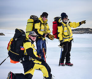 Three expeditioners rest, on kneeling and the others standing