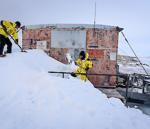 Expeditioners dig snow and ice from around hut