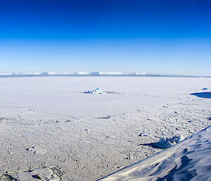 An expeditioner dressed in red winter gear looks across the vast white Vanderford Glacier