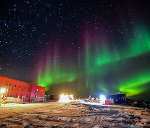 A spectacular green and red aurora in the night sky over Casey station