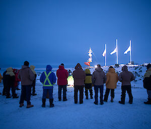 Expeditioners stand in a line facing those running the dawn service