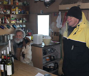 Expeditioners sit at the dining table inside the hut