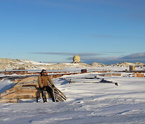 Expeditioner sits on one of the snow-covered structures at Wilkes